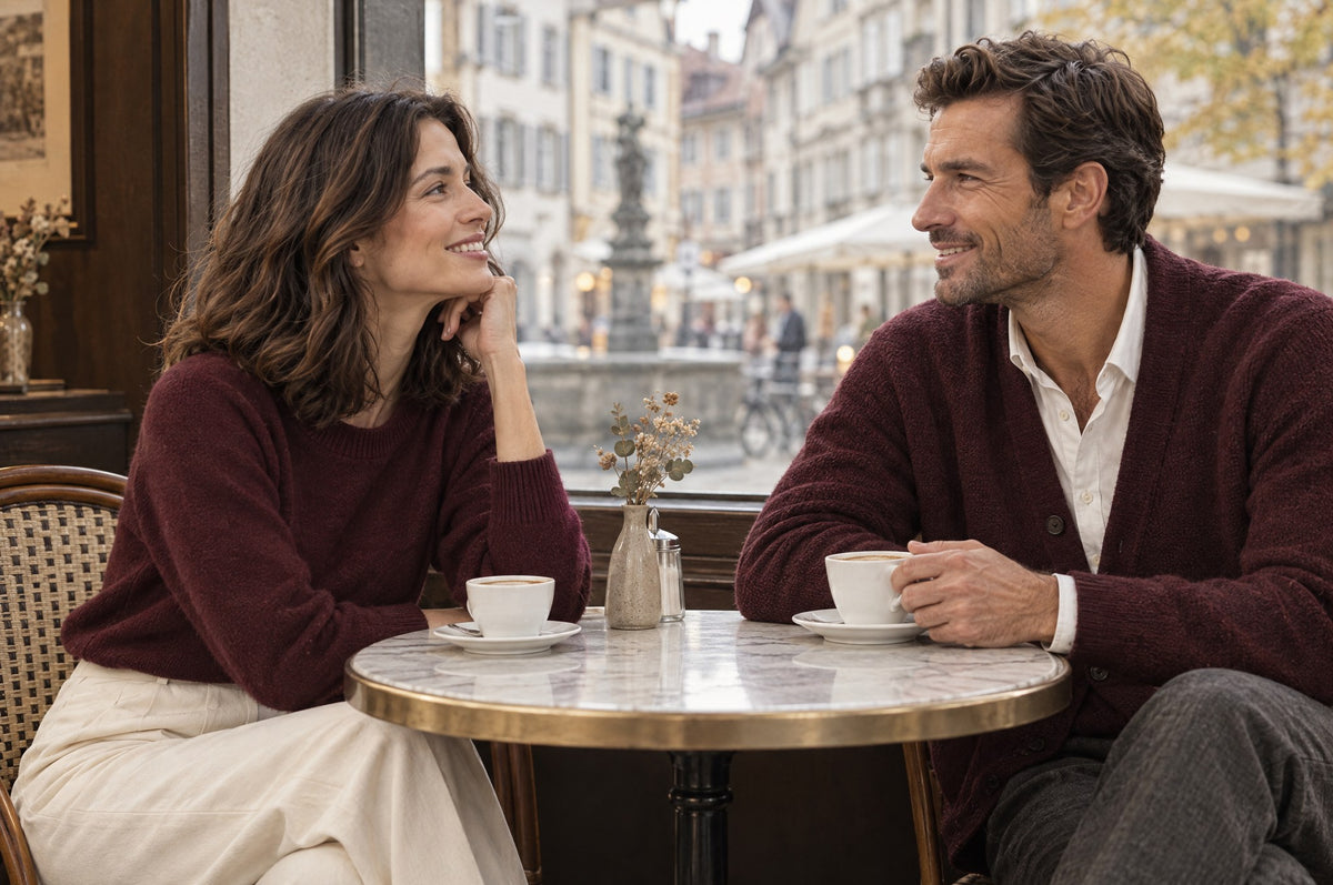 Frau und Mann in bordeauxfarbenem Strick lachen an einem Cafétisch in Zürich